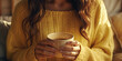 mujer sosteniendo una taza de café entre sus manos, sobre fondo de salón desenfocado