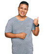 © Krakenimages.com - Young latin man wearing casual clothes smiling with happy face looking and pointing to the side with thumb up.