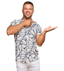 Poster - Handsome muscle man wearing casual clothes amazed and smiling to the camera while presenting with hand and pointing with finger.