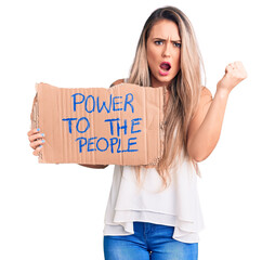 Poster - Young beautiful blonde woman holding power to the people cardboard banner annoyed and frustrated shouting with anger, yelling crazy with anger and hand raised