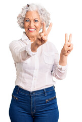 Wall Mural - Senior grey-haired woman wearing casual clothes smiling looking to the camera showing fingers doing victory sign. number two.