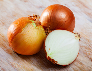 Wall Mural - Raw whole and sliced yellow onions on wooden background