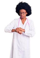 Poster - Young african american woman wearing doctor coat and stethoscope checking the time on wrist watch, relaxed and confident