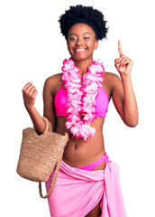 Canvas Print - Young african american woman wearing bikini and hawaiian lei surprised with an idea or question pointing finger with happy face, number one