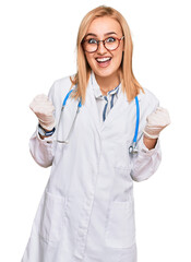 Wall Mural - Beautiful caucasian woman wearing doctor uniform and stethoscope celebrating surprised and amazed for success with arms raised and open eyes. winner concept.