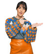 © Krakenimages.com - Young hispanic woman wearing casual clothes amazed and smiling to the camera while presenting with hand and pointing with finger.