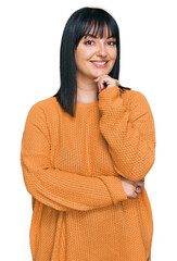 Young hispanic woman wearing casual clothes looking confident at the camera smiling with crossed arms and hand raised on chin. thinking positive.