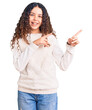 © Krakenimages.com - Beautiful kid girl with curly hair wearing casual clothes smiling and looking at the camera pointing with two hands and fingers to the side.