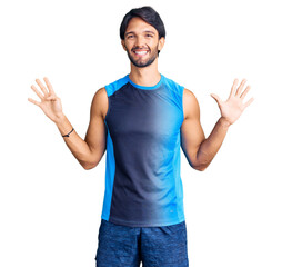 Canvas Print - Handsome hispanic man wearing sportswear showing and pointing up with fingers number nine while smiling confident and happy.