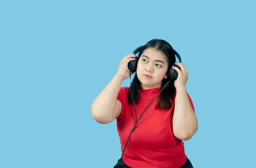 Wall Mural - Portrait girl young woman asian chubby fat cute beautiful pretty one person wearing a red shirt, listening to music sound through a smartphone headphone happy fun enjoy in isolated blue blackgrond