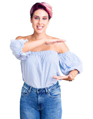 Poster - Young beautiful woman with pink hair wearing casual clothes gesturing with hands showing big and large size sign, measure symbol. smiling looking at the camera. measuring concept.