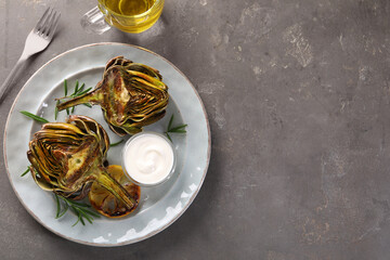 Wall Mural - Plate with tasty grilled artichoke served on grey table, flat lay. Space for text