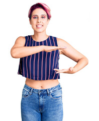 Poster - Young beautiful woman with pink hair wearing casual clothes gesturing with hands showing big and large size sign, measure symbol. smiling looking at the camera. measuring concept.