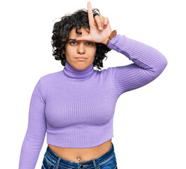 Canvas Print - Young hispanic woman with curly hair wearing casual clothes making fun of people with fingers on forehead doing loser gesture mocking and insulting.