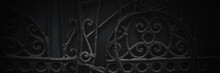 Old Broken Forged Iron Gates. Uneven Metal Surface Of Dark Gray Color With Curved Wrought Parts. Dark Wide Panoramic Background