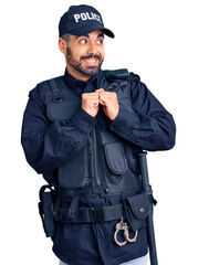 Wall Mural - Young hispanic man wearing police uniform laughing nervous and excited with hands on chin looking to the side