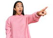 © Krakenimages.com - Young asian woman wearing casual winter sweater pointing with finger surprised ahead, open mouth amazed expression, something on the front
