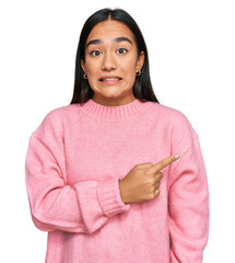 Wall Mural - Young asian woman wearing casual winter sweater pointing aside worried and nervous with forefinger, concerned and surprised expression