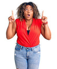 Wall Mural - Young african american plus size woman wearing casual style with sleeveless shirt amazed and surprised looking up and pointing with fingers and raised arms.