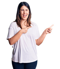 Poster - Young beautiful brunette woman wearing casual t-shirt smiling and looking at the camera pointing with two hands and fingers to the side.