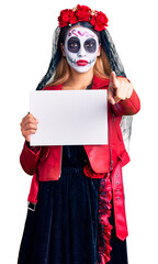 Sticker - Woman wearing day of the dead costume holding blank empty banner pointing with finger to the camera and to you, confident gesture looking serious