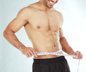 Poster - Measuring tape, stomach and fitness man in studio with weight loss, progress or bmi control on white background. Body, wellness and male model with waist measurement for diet, detox or sixpack check