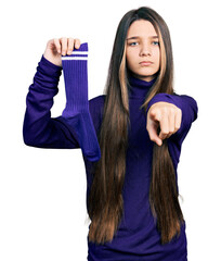 Wall Mural - Young brunette girl with long hair holding sporty sock pointing with finger to the camera and to you, confident gesture looking serious