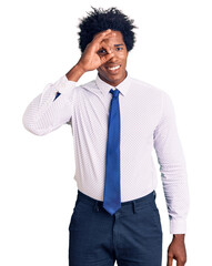 Wall Mural - Handsome african american man with afro hair wearing business clothes smiling happy doing ok sign with hand on eye looking through fingers