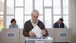 © Synthex🇺🇦 - A responsible senior man is throwing a ballot into the sealed box, making his choice during the elections