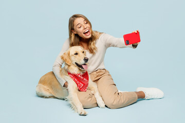 Wall Mural - Full body young owner woman with her best friend retriever dog wears casual clothes doing selfie shot on mobile cell phone isolated on plain light blue background studio. Take care about pet concept.