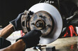 Auto mechanic installing car front brake caliper and brake pads.	

