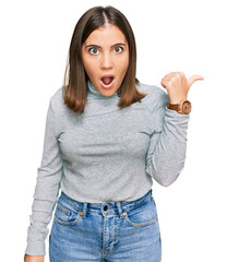 Poster - Young beautiful woman wearing casual turtleneck sweater surprised pointing with hand finger to the side, open mouth amazed expression.