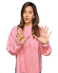 Poster - Young hispanic woman wearing casual clothes moving away hands palms showing refusal and denial with afraid and disgusting expression. stop and forbidden.