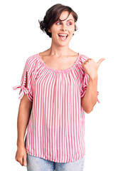 Sticker - Beautiful young woman with short hair wearing casual summer clothes smiling with happy face looking and pointing to the side with thumb up.