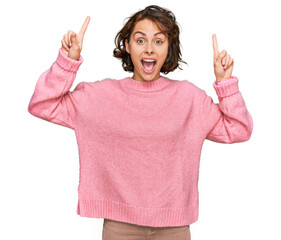 Sticker - Young hispanic woman wearing casual clothes smiling amazed and surprised and pointing up with fingers and raised arms.