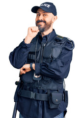 Poster - Young handsome man wearing police uniform looking confident at the camera smiling with crossed arms and hand raised on chin. thinking positive.