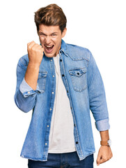 Wall Mural - Handsome caucasian man wearing casual denim jacket angry and mad raising fist frustrated and furious while shouting with anger. rage and aggressive concept.