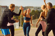 © Studio Romantic - Happy smiling sporty young friends giving high five to a woman rejoicing the success in sport training after jogging exercises outdoors. People standing in the park after workout in nature.