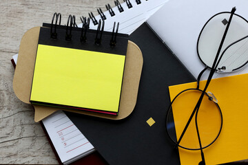 Wall Mural - blank yellow office sticker on notepad, on wooden background. Mockup.