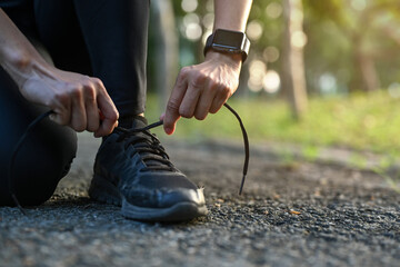  Close up sporty woman kneeling and tying shoelace ready for morning jogging