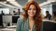 Portrait of young smiling Hispanic redhead business woman sitting on modern company office desk with coworkers in background