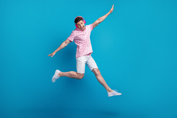 Canvas Print - Full size photo of cheerful overjoyed man jump arms wings flying listen music headphones isolated on blue color background