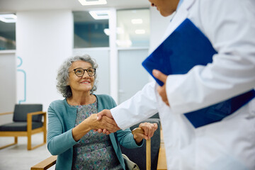 Happy senior woman greets her doctor in waiting room at medical clinic.