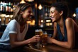 two women sharing light lager beers at a bar