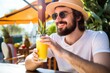 man drinking mango and pineapple smoothie outdoors