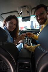 Wall Mural - Happy couple posing at camera in car interior