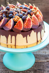 Wall Mural - Delicious cake with figs dipped into melted chocolate, pecan nuts, grapes, chocolate bites and cookies on the top. Concept of autumn or summer cake
