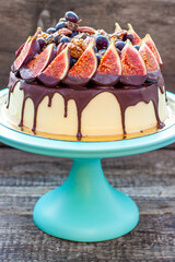 Wall Mural - Delicious cake with figs dipped into melted chocolate, pecan nuts, grapes, chocolate bites and cookies on the top. Concept of autumn or summer cake