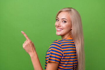 Poster - Profile side photo of adorable satisfied girl wear stylish clothes demonstrate empty space billboard isolated on green color background