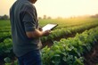 A man standing in a field holding a tablet. Suitable for technology, communication, and outdoor lifestyle themes